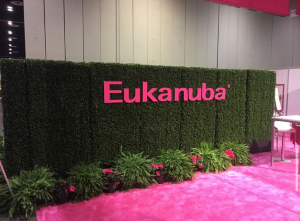 Green shrub wall featuring pink text, creating a vibrant and natural display