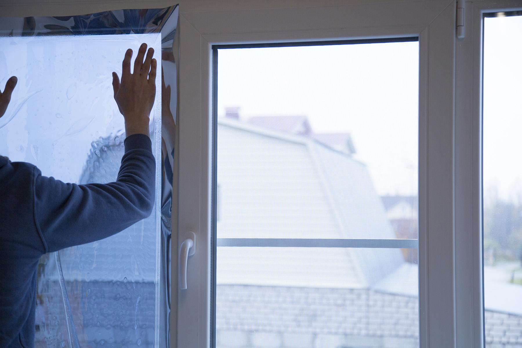 Man applying tinted window film to household window