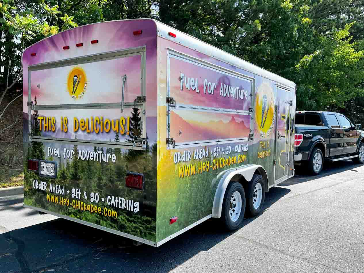 Full food trailer wrap with a mountain horizon background and logo graphics for Hey Chickadee in Hendersonville, NC