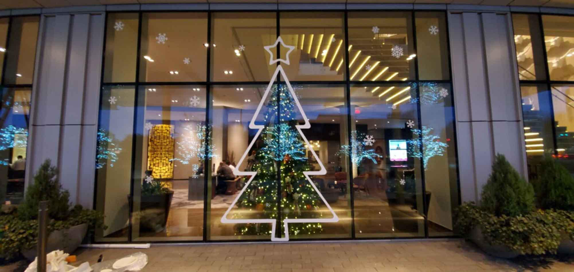 Image of seasonal window decals featuring the vinyl outline of a tree with the real tree on the other side of the window