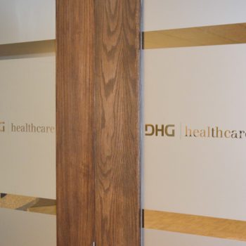 A pair of doors covered in window frosting with the words DHG | healthcare cut out.