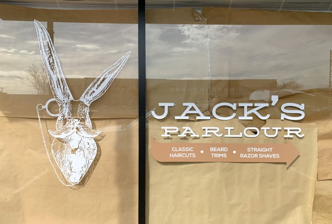 Intricate storefront window graphic of a barbershop's name, rabbit logo and services.