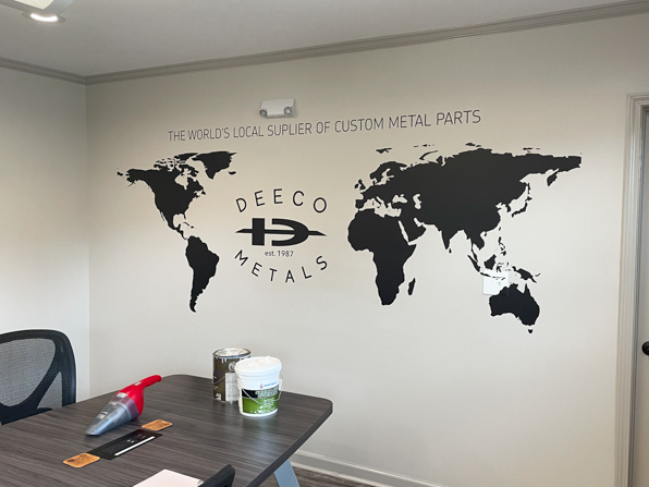 Black vinyl map on conference room wall with company logo in Atlantic Ocean.
