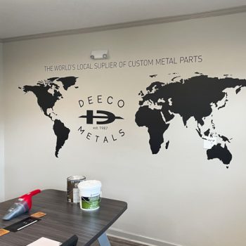 Black vinyl map on conference room wall with company logo in Atlantic Ocean.