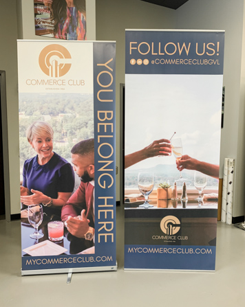Two retractable banner stands with people smiling and toasting.