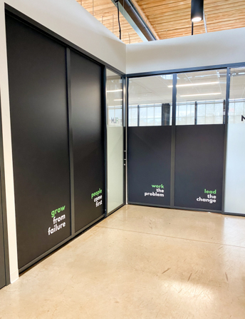 Full coverage window graphics in matte black with text in shared office space.