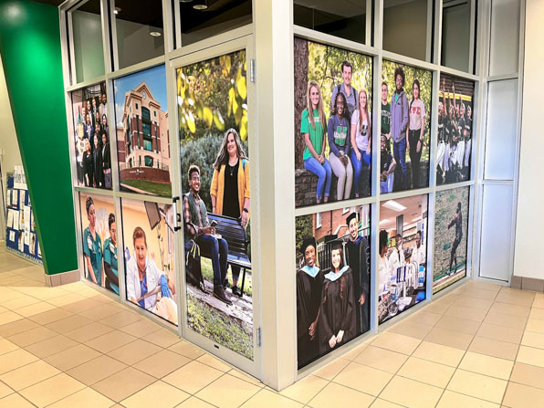 Interior window graphics of student life covering unused offices in USC Upstate's UCG space.