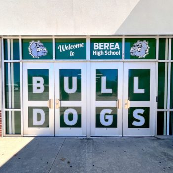 Custom school mascot window graphics on high school's athletics program glass covered entrance .