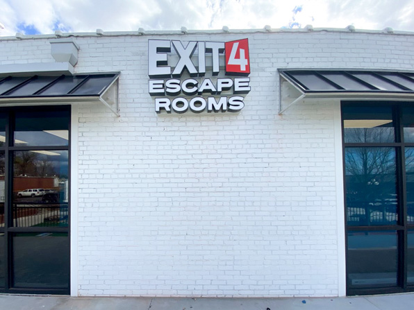 Business signage for Exit 4 Escape Rooms on exterior brick wall.