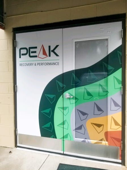 Storefront window and door graphics with an abstract logo pattern for a Peak.