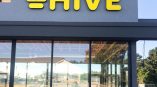 Yellow illuminated storefront signage for Hive.