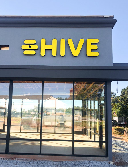 Yellow illuminated storefront signage for Hive.