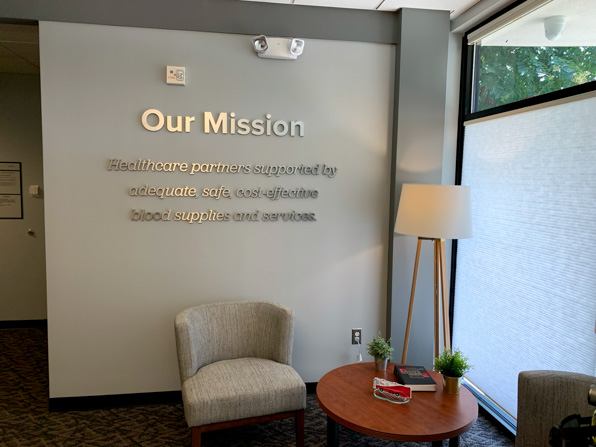 Brushed aluminum dimensional lettering of the Blood Connection mission statement in lobby.