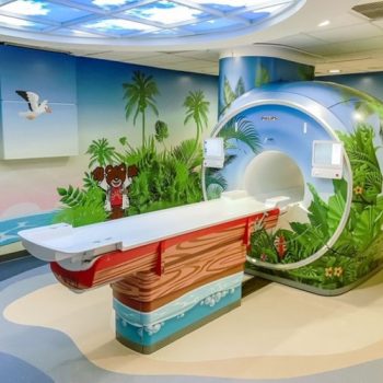 MRI room in a children's hospital with the table, MRI machine and walls covered with beach themed vinyl wraps.
