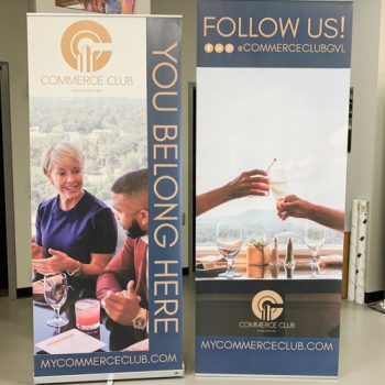 Two retractable banner stands with people smiling and toasting.
