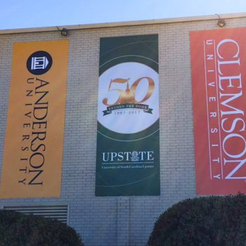 Wide-format banners hanging from the side of a building representing universities.