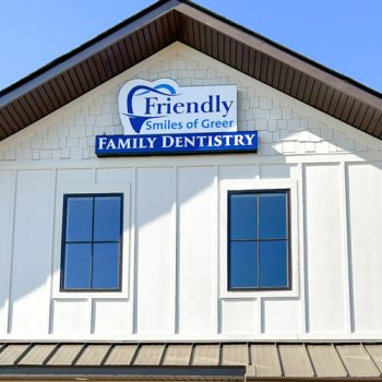 Storefront signage with logo for Friendly Smiles of Greer installed just below the building's apex