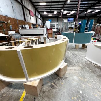 Solid color vinyl wraps for two rounded desks being produced in a warehouse