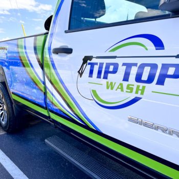 Up close photo of a partial wrap on a truck for Tip Top Wash featuring the logo and water pattern