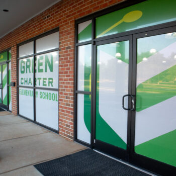 White storefront window perf with green logo on cafeteria windows for Green Charter Elementary School in Greenville, SC