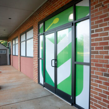 White storefront window perf with green logo on classroom windows for Green Charter Elementary School in Greenville, SC