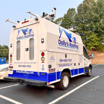 Bright blue logo, contact info and services on a service van for Dolly's Roofing in Greenville, SC