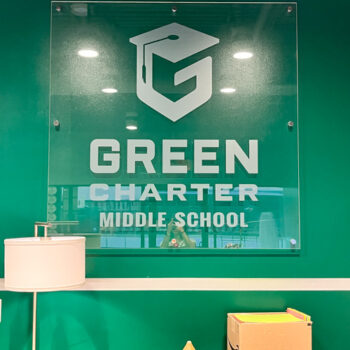 Acrylic display with frosted logo installed on a green wall at Green Charter Middle School in Greenville, SC