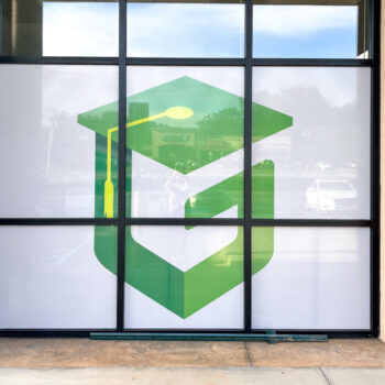 White storefront window perf with green logo for Green Charter School of Spartanburg, SC