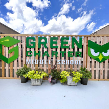 Custom dimensional acm sign on wooden fence withlogo and mascot on either side for Green Charter Middle School