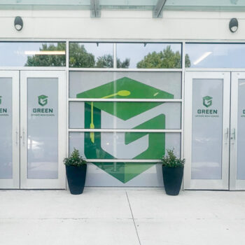 White storefront window perf with green logos for Green Charter High School of Greenville, SC