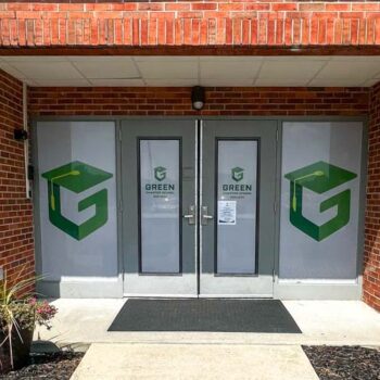 White storefront window perf with green logos for Green Charter School of Columbia, SC