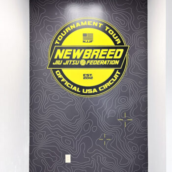 Custom interior wall mural overlaying yellow badge logo on grey topical background for Newbreed in Greenville, SC
