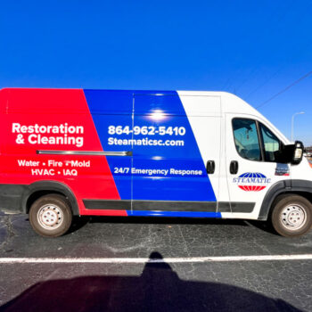 3/4 van wrap featuring bright blue and red colors with business info in white for Steamatic in Greenville, SC