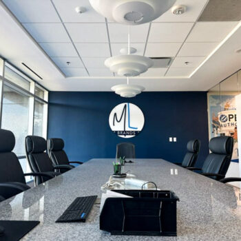 Custom acrylic logo with white and blue logo design installed on a blue conference room wall at Main Line Brands