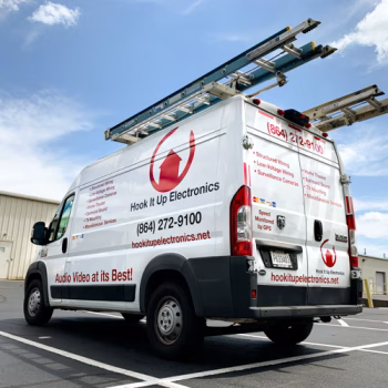 Custom cut lettering on a Hook It Up Electronics Promaster van that showcases the company's services, contact info, and branded red and black coloring.