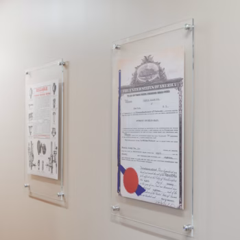 Acrylic displays installed with standoffs displaying prints of old, treasured documents from Reliable's history in their marketing wing at the HQ in Liberty, SC.