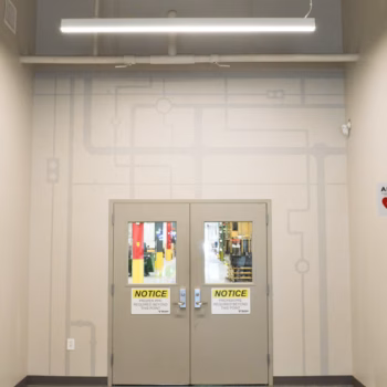 Pipe themed wall decals custom cut from grey vinyl surrounding the doors to the factory at Vermeer's Piedmont, SC facility.