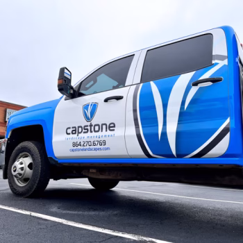 Signature Capstone Landscaping blue trim with logos and contact info on their crew cab flatbed truck.