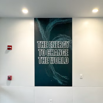 Narrow wall graphic showcasing one of GE Vernova's slogans and energy particle graphic.