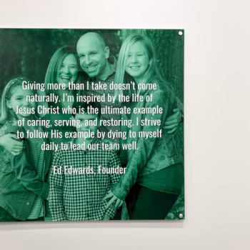 Acrylic wall display with standoffs with a quote from the company's founder.
