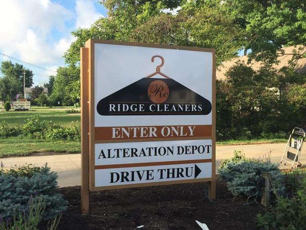 Outdoor roadside sign for Ridge Cleaners featuring drive-thru and alteration services.