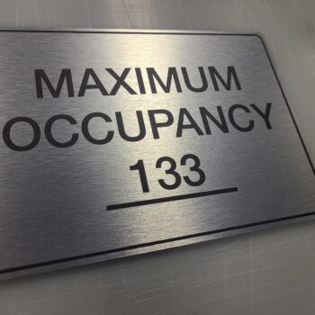 ADA signage for an office that is brushed metal looking.