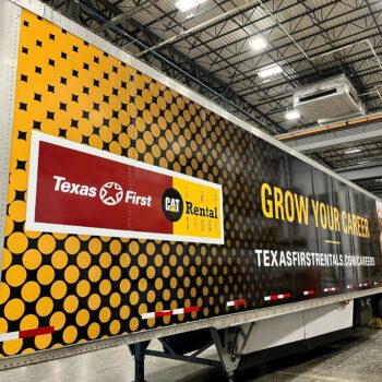 Side of semi trailer wrapped in car vinyl with company logo and promotional text.