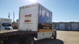 The back of a box truck wrapped in vinyl with a picture of a team and promotional text