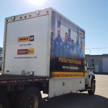 The back of a box truck wrapped in vinyl with a picture of a team and promotional text