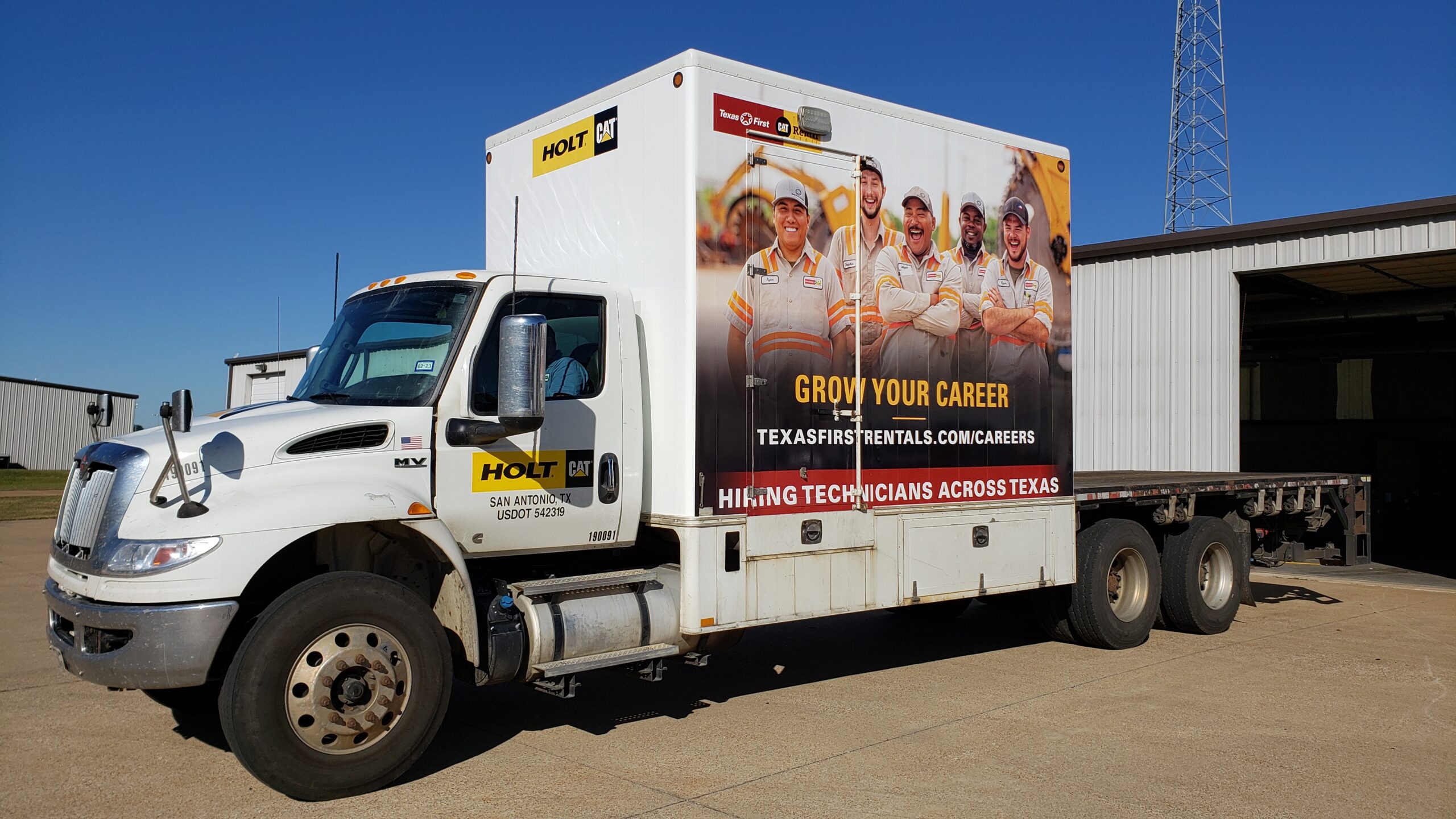 The side of a box truck wrapped in vinyl with a picture of a team and promotional text