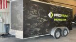 Side of a trailer with panel car wrap with company logo and black and grey camo graphics.
