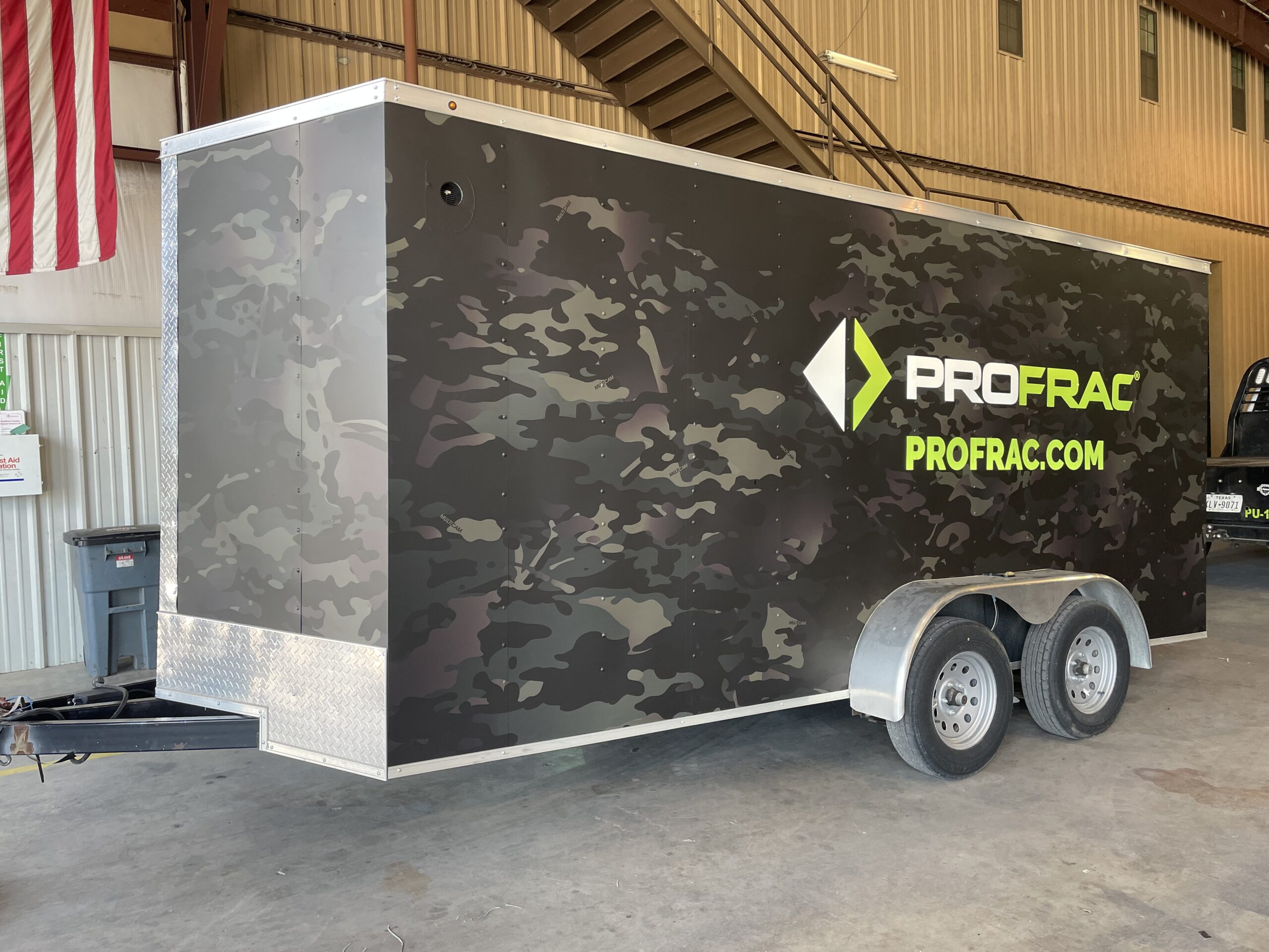 Side of a trailer with panel car wrap with company logo and black and grey camo graphics.