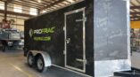 Front side of a trailer with black panel car wrap with company logo and camo graphics.