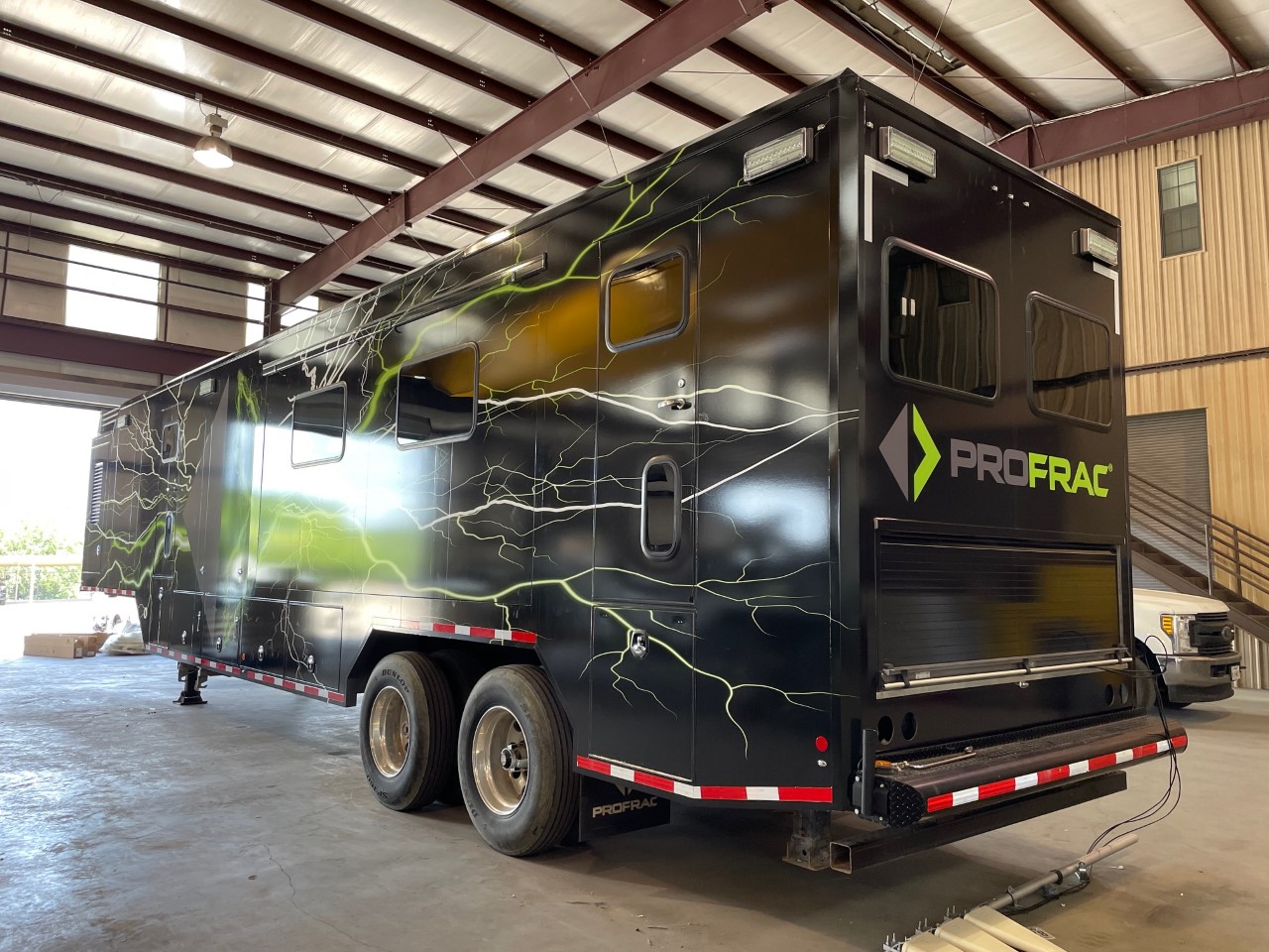 Back side of a 54 foot data trailer with black panel car wrap with company logo and green graphics.